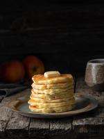 Pancake with butter. Side view, copy space, vertical. Dark moody old rustic wooden background. photo