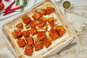 tray with roasted pieces of sweet pumpkin with honey and seasonings, top view photo