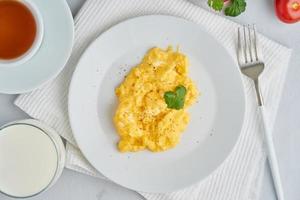 Breakfast with pan-fried scrambled eggs, cup of tea, glass of milk photo