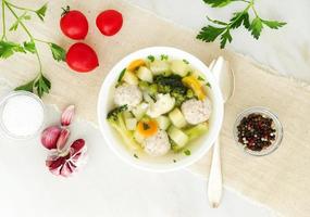 bowl of soup, a cup of broth and vegetables, meatballs made of turkey and chicken, top view photo