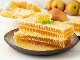 honey in honeycomb, close-up, on brown ceramic plate, on wooden rustic table, side view photo