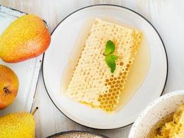 honey in honeycomb, close-up, on ceramic plate, on white wooden rustic table, flat lay photo