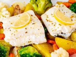 Fish cod baked with vegetables - healthy diet healthy food. Light white marble photo