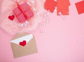 gift in red gift box with bow, smart phone, envelope, card, red heart, pink background, flat lay, copy space, mockup photo