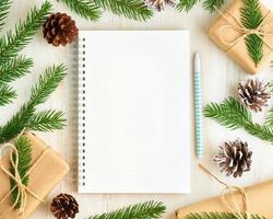 White open notepad, bullet journal and Christmas decoration lying on white wooden background, flat lay, copyspace. Hand crafted, plastic free, zero waste concept. Mock up photo