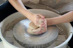 Woman making ceramic pottery on wheel, hands closeup, focus on potters, palms with pottery photo