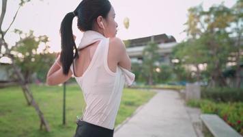 Young athlete Asia lady in sportswear warmings up before exercise by rotating her arms as well as turning her body left and right, morning soft sunlight, attractive female working out outside video