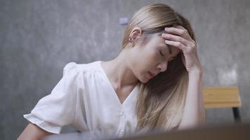 stressata, sopraffatta, giovane donna d'affari in abito casual che lavora al computer, soffre di affaticamento degli occhi o ha sentimenti dolorosi, concetto di sindrome da burnout professionale delle persone asiatiche, dipendente stanco video