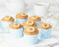 muffin de plátano, pastelitos en papel de cajas de pastel azul, vista lateral, primer plano, mesa de hormigón blanco foto