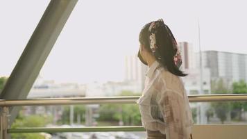 Young Asian female wear black protective mask standing and looking at time in metro station, covid-19 lady wait for friends, appointment meet up, self protection on public transport, golden sunset video