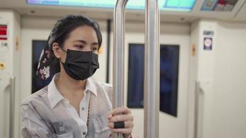 Beautiful Asian Wear black mask stand hold on to pole inside subway car looking down, depress sad and hopeless emotional tiring day, covid-19 new normal, risk on public transport, social distance