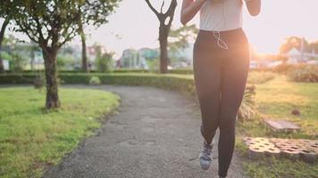 jovem mulher ativa usa roupas esportivas correndo dentro do parque, bela luz do sol da manhã no fundo, exercício cardio, ouvindo música enquanto corre sozinho, energia positiva, corpo em forma e forte video