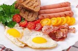 desayuno inglés - huevos fritos, tocino, salchichas y pan de centeno tostado foto