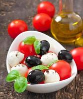 Fresh salad with cherry tomatoes, basil, mozzarella and black olives.