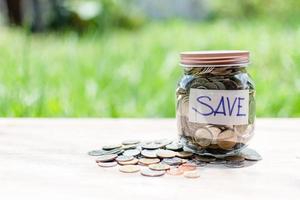 Blurred background, Coins and text SAVE in a glass jar placed on a wooden table. Concept of saving money for investment and emergency situations. Close up photo