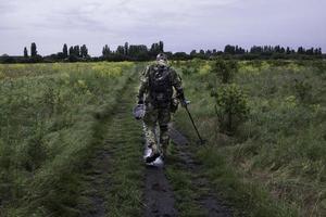 Soldier using a metal detector in fields