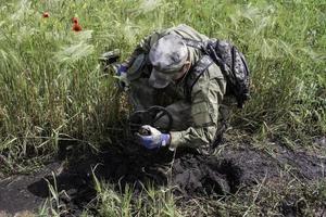 soldado usando un detector de metales en los campos