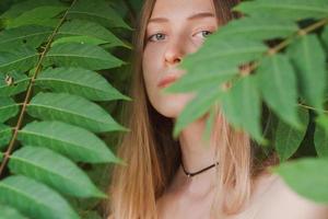 retrato de una bella joven con hojas verdes, una bella dama rubia con arbustos de primavera foto