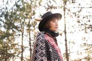 Yong hipster woman traveler in hat and poncho walking outdoors photo