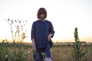 mujer joven pelirroja con pecas en vestido vintage hecho a mano caminar en campos con flores foto