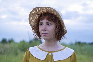Young redhead woman with freckles in vintage handmade dress walk in fields with flowers photo