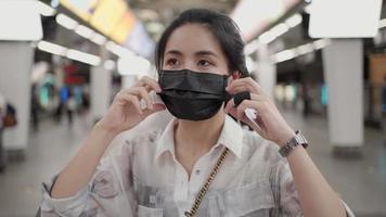 aziatische vrouw die zwart masker verwijdert, terwijl ze op het platform van het metrostation staat, covid-19, meisje in het metrostation, nieuwe normale levensstijl, zelfbescherming, openbaar vervoer, sociale afstand