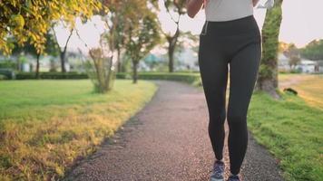 sportliche frau trägt schwarze leggings beim joggen im park auf der laufbahn während des sonnenuntergangs, wird wieder fit, bleibt stark und fit, morgensonnenlicht läuferin, erfrischende outdoor-aktivitäten video
