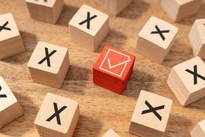 Right or good decision making concept. Check mark symbol and wrong or cross icon on wooden cubes photo