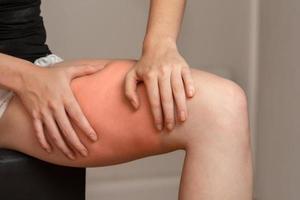 The girl thigh pain she is using a hand massage on her thighs. photo