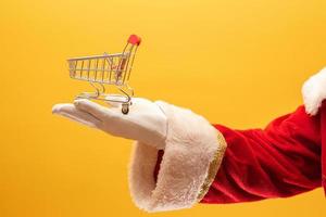 santa claus y el supermercado, muestra un mini carrito. concepto de navidad y compras. foto