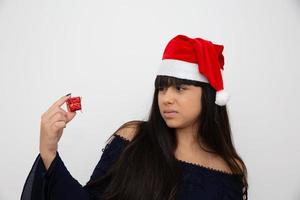 Young woman in santa cap holding christmas present photo