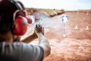 Detail view of shooter holding gun and training tactical shooting, focus on pistol. Shooting range.