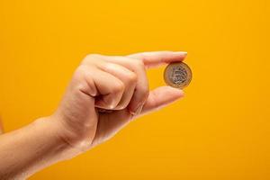 Hand holding one Real coin of Brazil on yellow background. Finance concept. photo