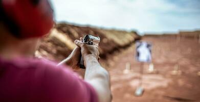 Detail view of shooter holding gun and training tactical shooting, focus on pistol. Shooting range. photo