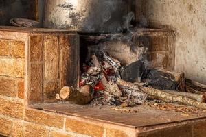 Estufa de leña encendida con una cacerola grande arriba foto