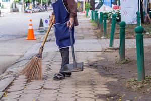 mujer joven barrió basura con escoba foto