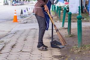 Young woman swept garbage by broom. photo