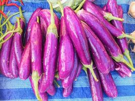 pila de berenjenas moradas a la venta en el mercado. foto