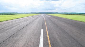 vista aérea de la pista de aterrizaje pavimentada del avión en brasil. pequeños aviones de hélice pista de aterrizaje remota con plantaciones de caña de azúcar en el fondo. foto