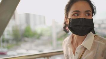 Asian young adult female wear black face mask walking on the elevated public walking path, covid-19 virus prevention video