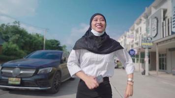 jeune femme musulmane asiatique courant le long de la rue pendant la pandémie de covid, se sentant heureuse positive, se précipitant le long de la rue par une journée ensoleillée, nouveau coronavirus normal, liberté vie heureuse visage souriant video