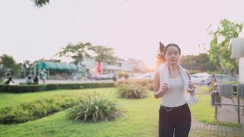 giovane donna asiatica che corre all'interno del parco durante l'ora d'oro del tramonto, stile di vita sano e moderno della donna, motivazione sportiva, sforzo personale, routine di allenamento per la perdita di peso, controllo dell'assunzione di calorie nutrizionali video