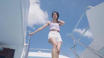 jovem mulher asiática descendo as escadas do navio de cruzeiro com vento soprando no rosto e cabelo, destinos de viagens de aventura, transporte público alternativo, balsas cruzando a ilha, férias de verão video