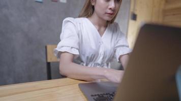 Asian blonde female office worker using laptop computer doing work research gathering information for master degree final thesis project, using laptop for learning, typing on keyboard, at home office video