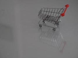 Supermarket shopping cart mini model placed on mirror table with reflection photo