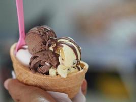 chocolate, té tailandés de naranja, helado de leche de coco en una taza de gofre crujiente en la mano de una mujer foto