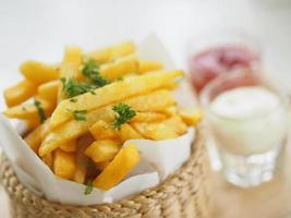 French fries, Potato chips Yellow crispy fries in wooden basket, snack delicious photo