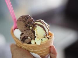 Chocolate, orange Thai tea, coconut milk ice cream in a crispy waffle cup in woman hand photo