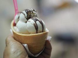 helado de leche de coco en una taza de gofre crujiente en mano de mujer foto