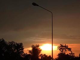 Night sunset shines bright abstract silhouette black bush tree on orange light sun cloud sky nature background photo